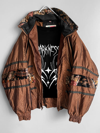 Giacca marrone con motivi floreali appesa a un gancio su uno sfondo bianco